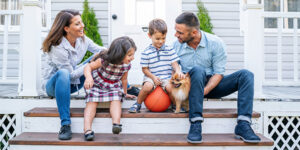 A family sitting on the front porch of their home